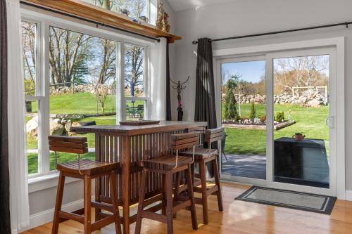 a kitchen with a bar with chairs and windows at Zen-Designed Guest Suite with PRIVATE 2-mile Trail Loop in Uxbridge