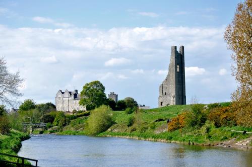 a castle on a hill next to a river at Highfield House Guesthouse in Trim