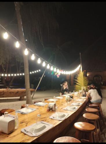 a long wooden table with chairs and lights at Tikipalmbeachhotel in Paje