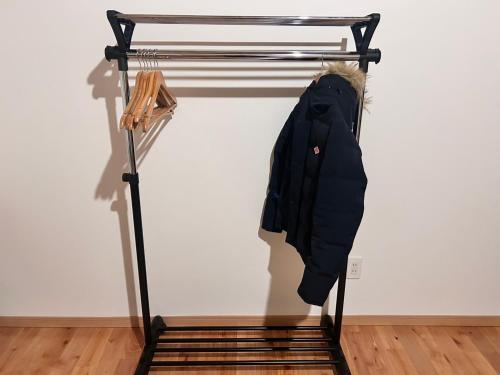a black coat hanging on a rack in a room at Guest House & Cafe Yamaboushi in Tsushima