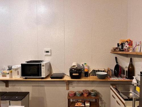 a kitchen counter with a microwave and a sink at Guest House & Cafe Yamaboushi in Tsushima