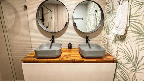 a bathroom with two sinks and two mirrors at Edificio Atalanta en el corazón de Medellín in Medellín