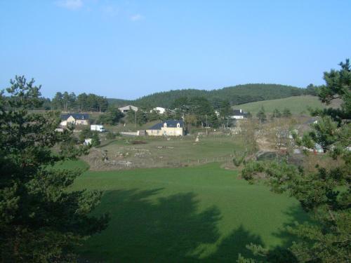 a large green field with houses on a hill at Chez Louis chambres d'hôtes à la ferme in La Canourgue
