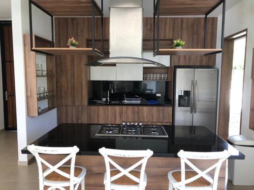 a kitchen with a black counter and white appliances at Hermosa Casa de Lujo en LAGO CALIMA in Darién