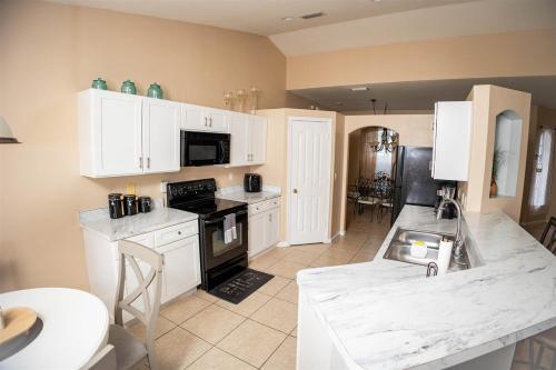 a kitchen with white cabinets and a stove top oven at A Home Where Memories Are Made in Port Saint Lucie
