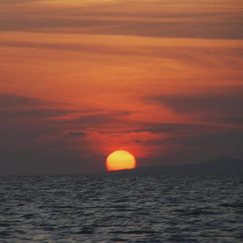 a sunset over the ocean with the sun in the sky at Patrick's on the Beach Resort in General Luna