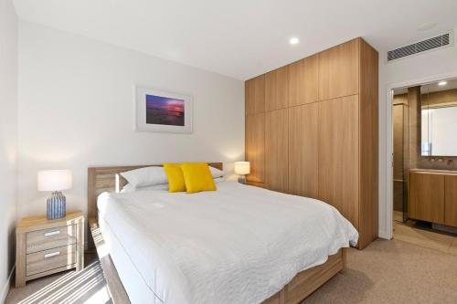 a bedroom with a large bed with yellow pillows at Lux Style Spacious 1 Bed Apt, Pool , Parking in Brisbane