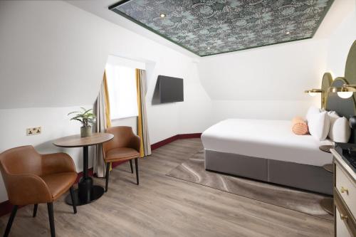 a hotel room with a bed and a table and chairs at The Welbeck Hotel by IHG in London