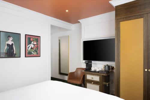 a bedroom with a bed and a flat screen tv at The Welbeck Hotel by IHG in London
