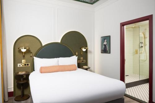 a bedroom with a white bed and a shower at The Welbeck Hotel by IHG in London