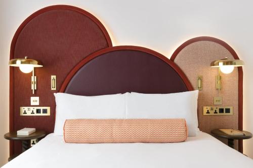 a bedroom with a large bed with a large headboard at The Welbeck Hotel by IHG in London