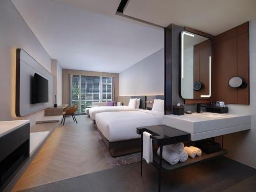 a hotel room with two beds and a sink and a mirror at AC Hotel by Marriott Chengdu North in Chengdu