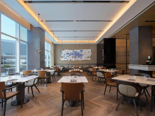 a dining room with tables and chairs and windows at AC Hotel by Marriott Chengdu North in Chengdu