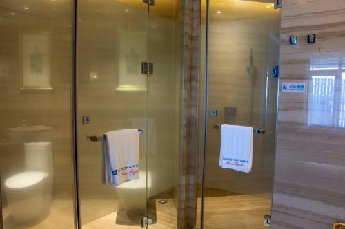 a bathroom with a glass shower and a toilet at Wyndham Grand Plaza Royale Wenchang in Wenchang