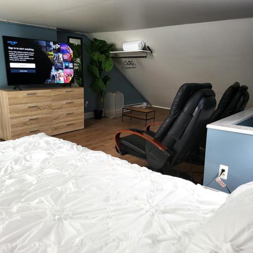 a bedroom with a bed and two chairs and a flat screen tv at Center to all 2 BR near hospitals, colleges, restaurants, events in Allentown