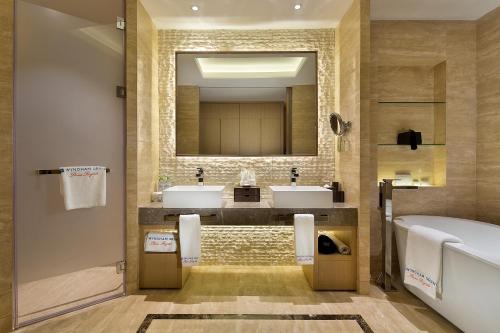 a bathroom with two sinks and a tub and a mirror at Wyndham Grand Plaza Royale Wenchang in Wenchang