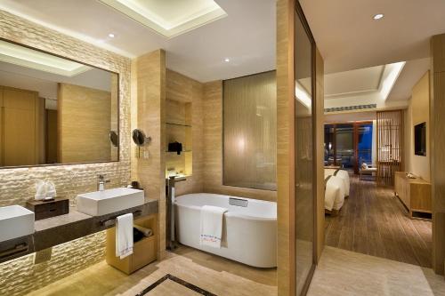 a bathroom with a tub and a large mirror at Wyndham Grand Plaza Royale Wenchang in Wenchang