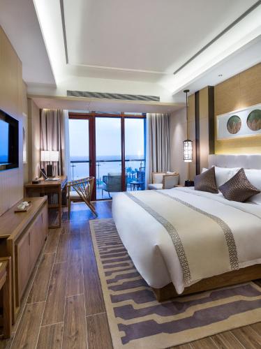 a hotel room with a large bed and a desk at Wyndham Grand Plaza Royale Wenchang in Wenchang
