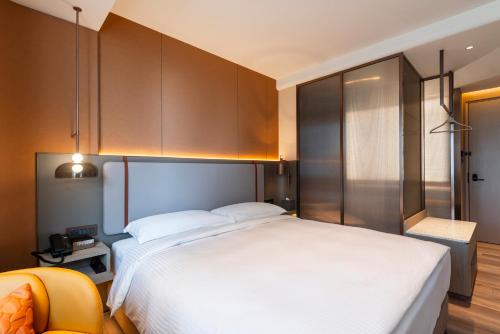 a bedroom with a large white bed and a chair at 采寓halo house in Taichung