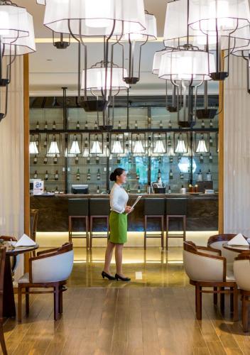 a woman standing in front of a bar in a restaurant at Wyndham Grand Plaza Royale Wenchang in Wenchang