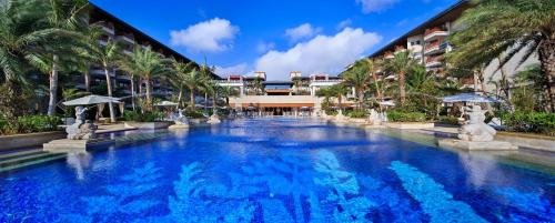 a large swimming pool with palm trees and buildings at Wyndham Grand Plaza Royale Wenchang in Wenchang