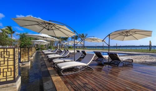 a row of lounge chairs and umbrellas on a deck at Wyndham Grand Plaza Royale Wenchang in Wenchang