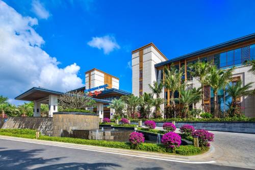 a building with pink flowers in front of it at Wyndham Grand Plaza Royale Wenchang in Wenchang