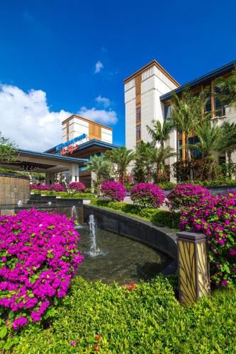 a garden with pink flowers in front of a building at Wyndham Grand Plaza Royale Wenchang in Wenchang