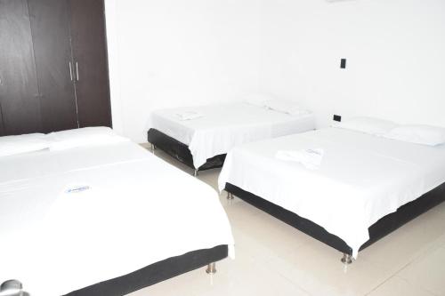 two beds in a room with white walls at Hotel Barcelona in Montería