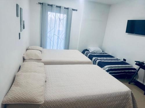 three beds in a room with a window at Hotel Barcelona in Montería
