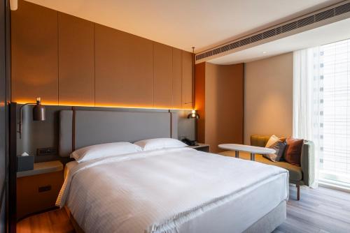 a bedroom with a large white bed and a chair at 采寓halo house in Taichung
