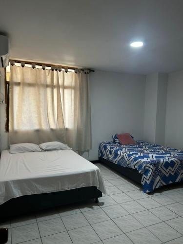 a bedroom with two beds and a window at Hostal Tayrona in Santa Marta