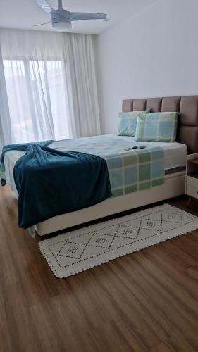 a bedroom with a bed with a green blanket and a window at Suíte tripla com vista piscina em casa familiar de luxo em Itaipu in Niterói