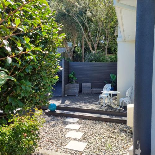 a garden with a blue fence and a patio at Riverstone Retreat Upper Hutt in Upper Hutt