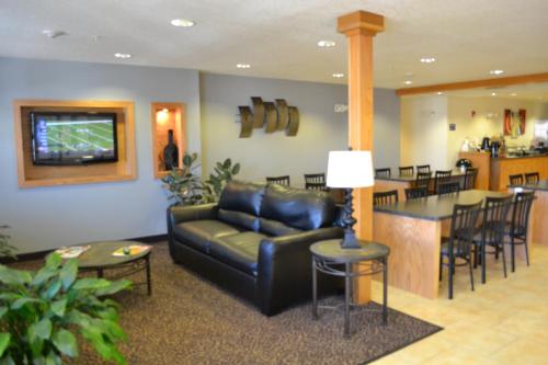 a living room with a black leather couch and a bar at Microtel Inn & Suites Tomah in Tomah