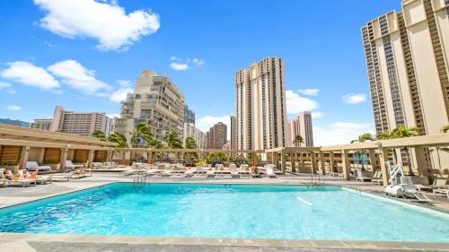 a large swimming pool with lounge chairs and buildings at Ala Moana Hotel 13th FL Partial Ocean View in Honolulu