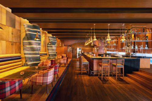 a restaurant with a bar with chairs and tables at ITC Sonar, a Luxury Collection Hotel, Kolkata in Kolkata
