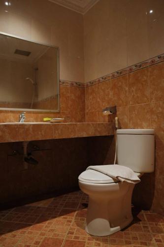a bathroom with a toilet with a mirror and a sink at Khas Parapat in Parapat