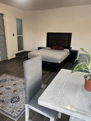 a bedroom with two beds and a chair and a table at Departamento Zona Hospital in Zamora de Hidalgo