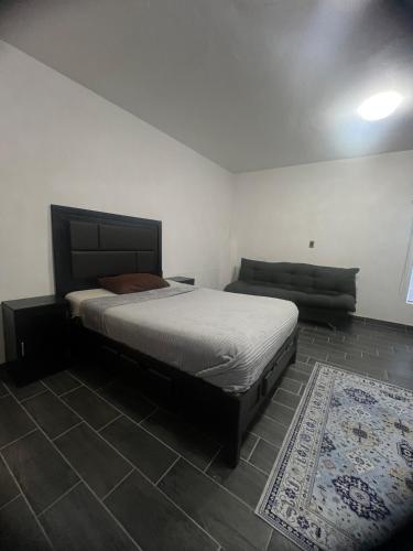 a bedroom with a bed and a couch and a rug at Departamento Zona Hospital in Zamora de Hidalgo