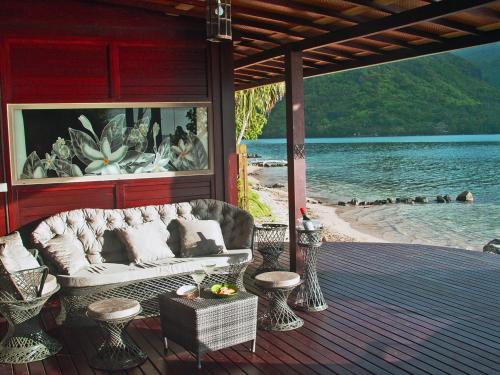 a couch sitting on a deck with a view of the water at Robinson's Cove Villas - Deluxe Wallis Villa in Papetoai