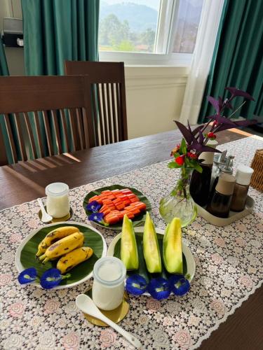 a table with plates of fruit and vegetables on it at Garden House Rice Field and Mountain View in Luang Prabang