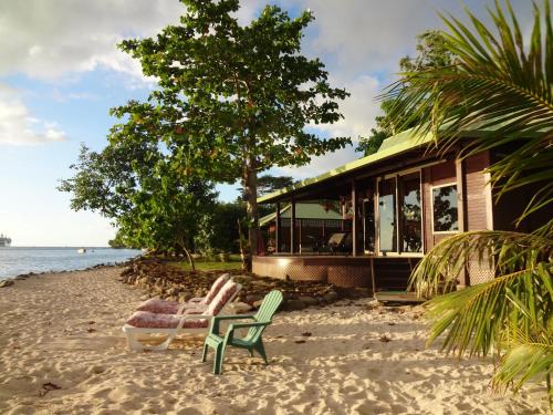 a house on the beach with two chairs on the sand at Robinson's Cove Villas - Deluxe Wallis Villa in Papetoai