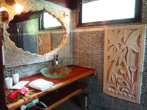 W łazience znajduje się umywalka i lustro. w obiekcie Robinson's Cove Villas - Deluxe Wallis Villa w mieście Papetoai