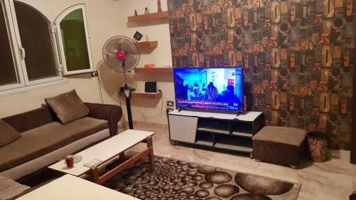 Una sala de estar con un sofá y un televisor de pantalla plana. en موقع متميز, en Al Ma‘şarah al Maḩaţţah