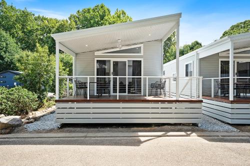 a house with a deck with two chairs on it at Myrtleford Holiday Park in Myrtleford