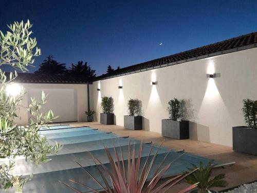 une cour avec des plantes en pot sur un mur blanc dans l'établissement Gîte familial avec piscine chauffée à Bretignolles-sur-Mer - FR-1-426-572, à Bretignolles-sur-Mer