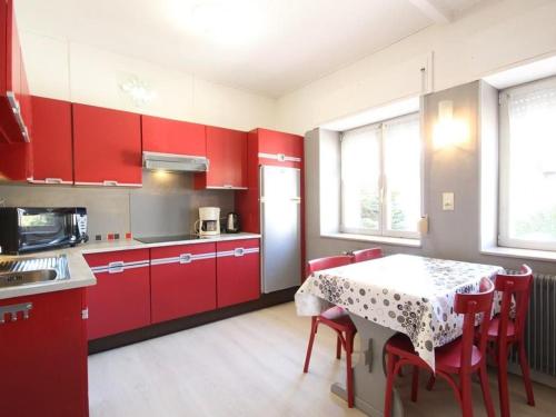 une cuisine avec des placards rouges et une table avec des chaises dans l'établissement Gîte paisible au pied du Bassin de Champagney, animaux acceptés - FR-1-583-372, à Champagney