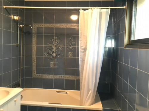 La salle de bains est pourvue d'une baignoire et d'un rideau de douche. dans l'établissement Grande maison familiale au Roaliguen, vue mer - FR-1-639-133, à Sarzeau