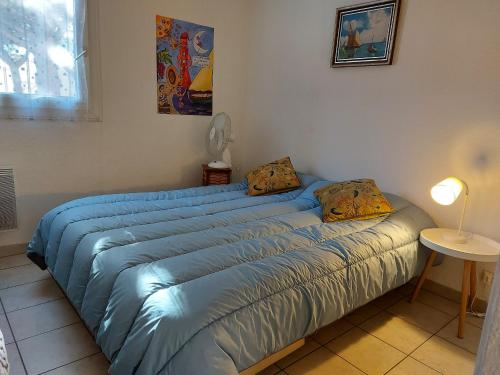 - un lit avec une couette bleue dans l'établissement Appartement 3 pers avec terrasse proche plage et commerces - FR-1-776-123, à Argelès-sur-Mer